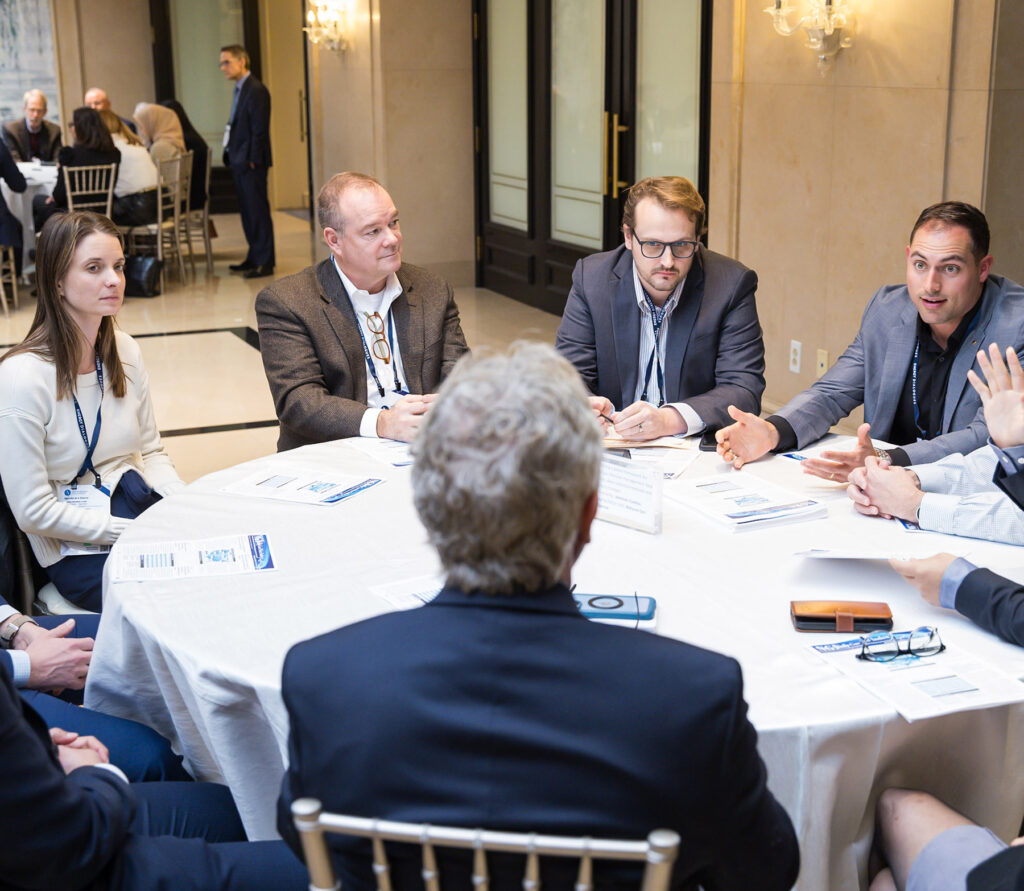 Several event attendees siting around a round table deep in discussion.